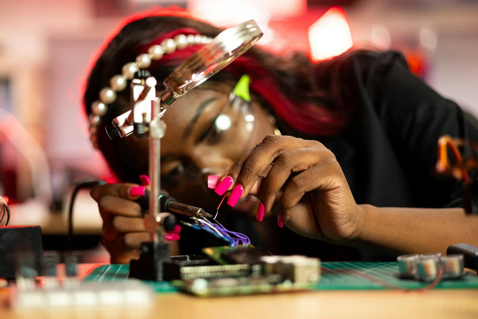 Technician soldering fine wires on an electronics assembly under magnification