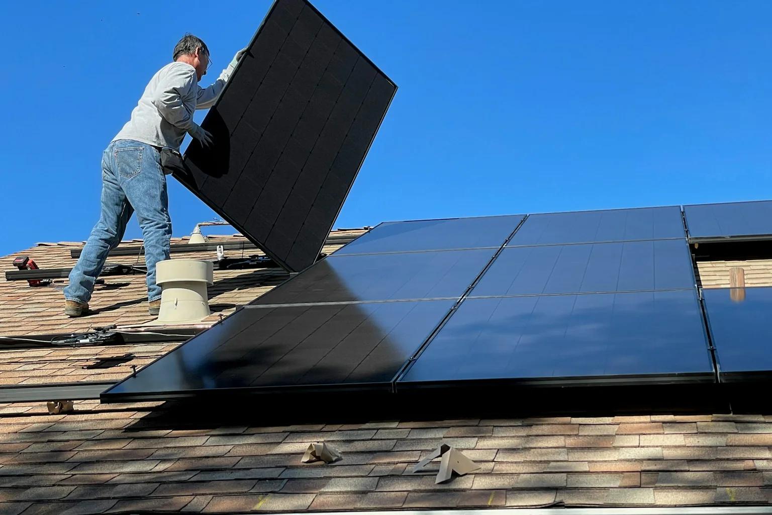Installer positioning a photovoltaic panel on a residential roof