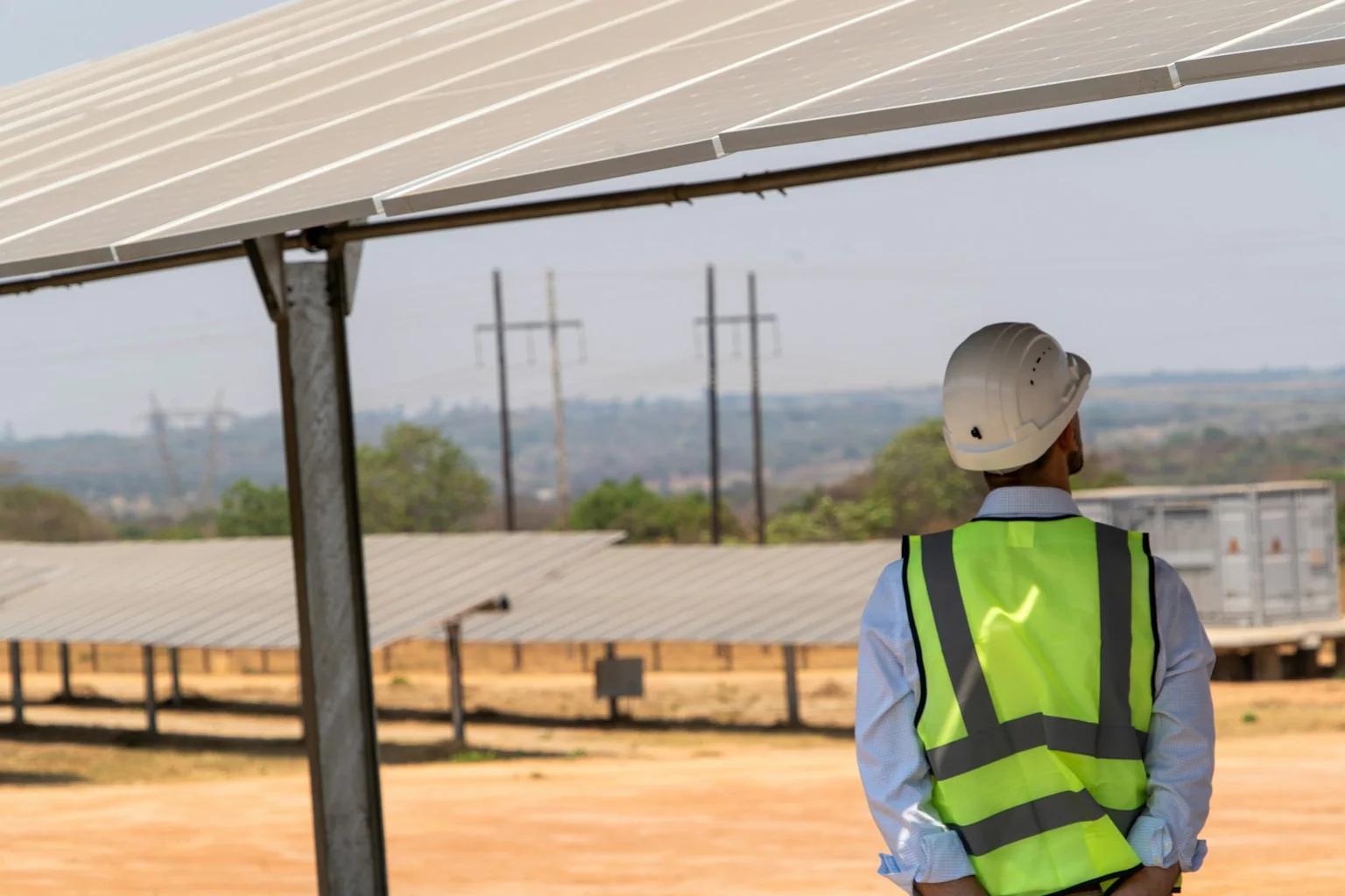 Site engineer inspecting rows of photovoltaic panels