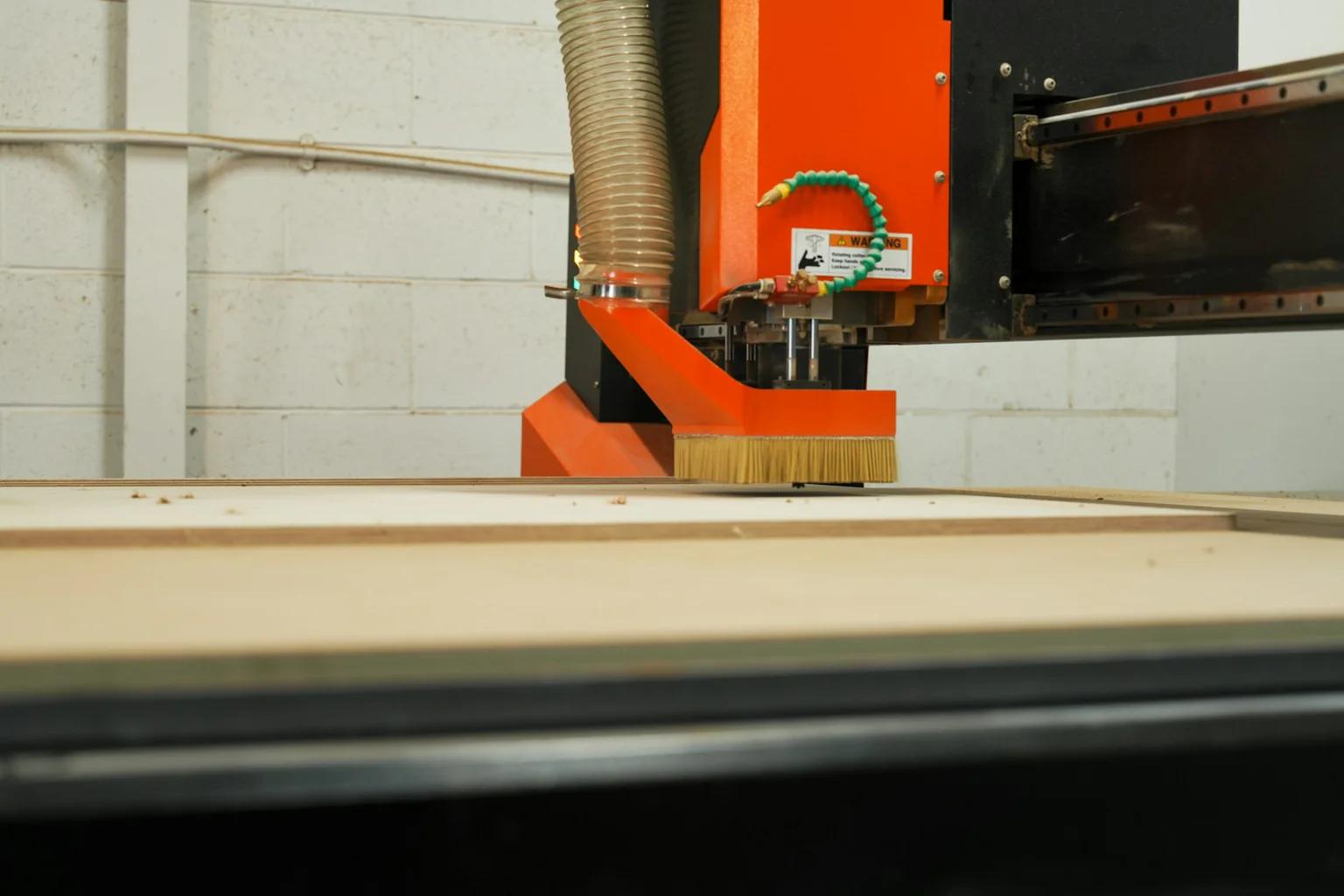Orange CNC router positioned over a sheet-material cutting bed