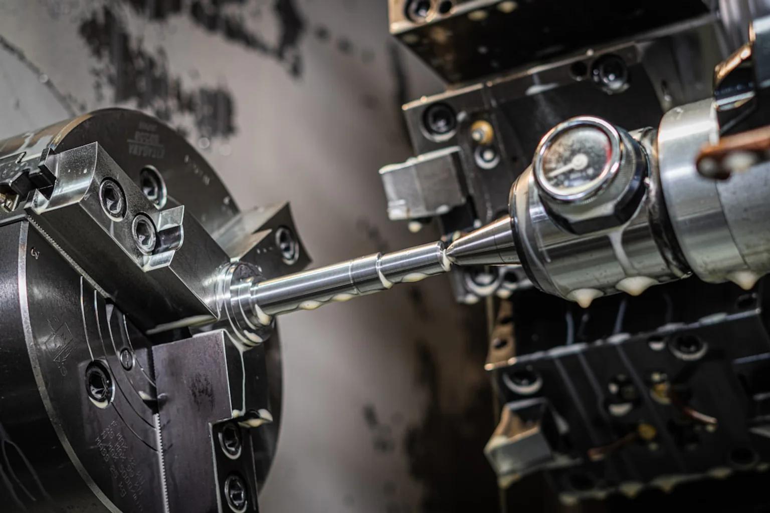 Cutting tool turning a cylindrical metal part on a CNC lathe