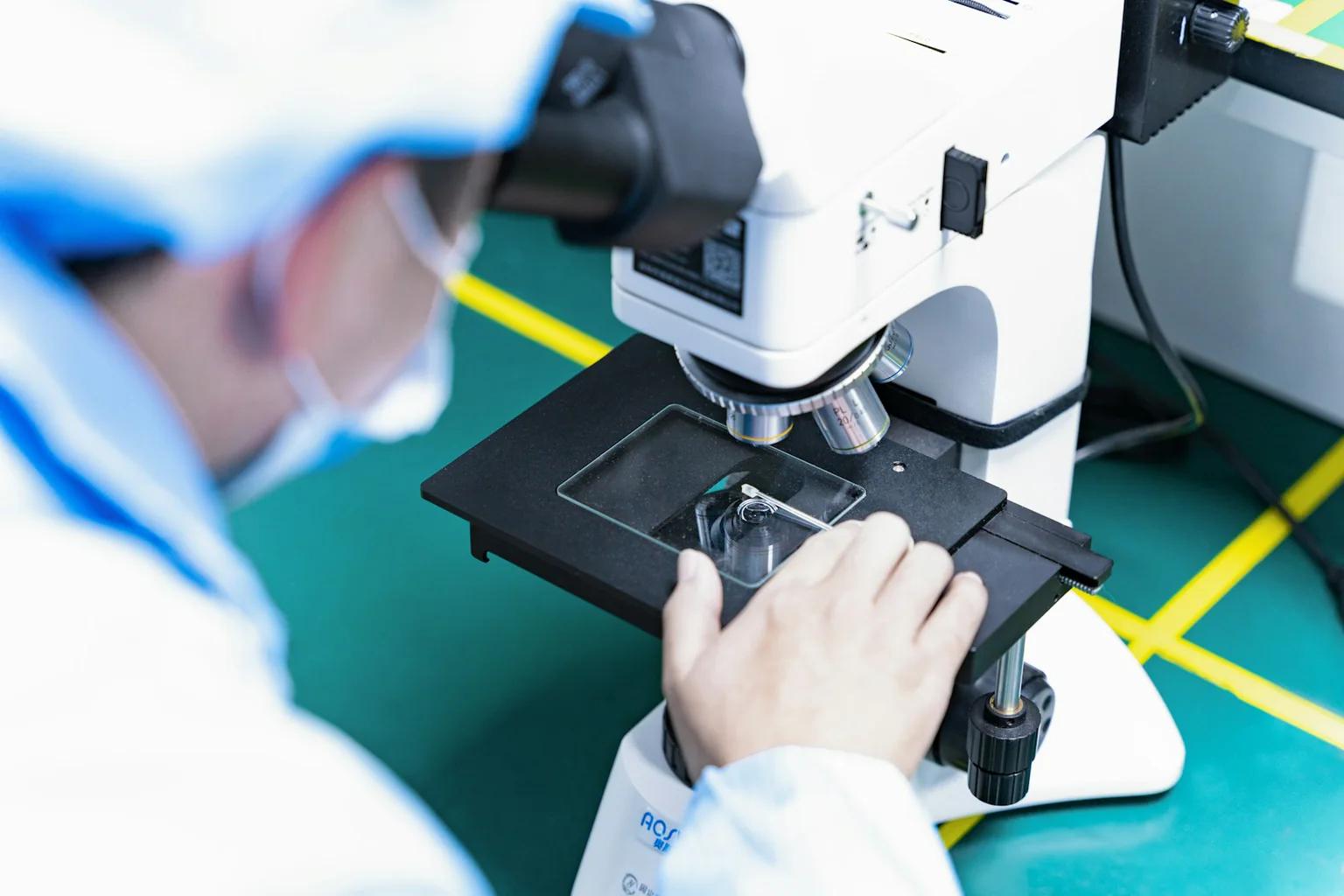 Technician inspecting a sample through a laboratory microscope