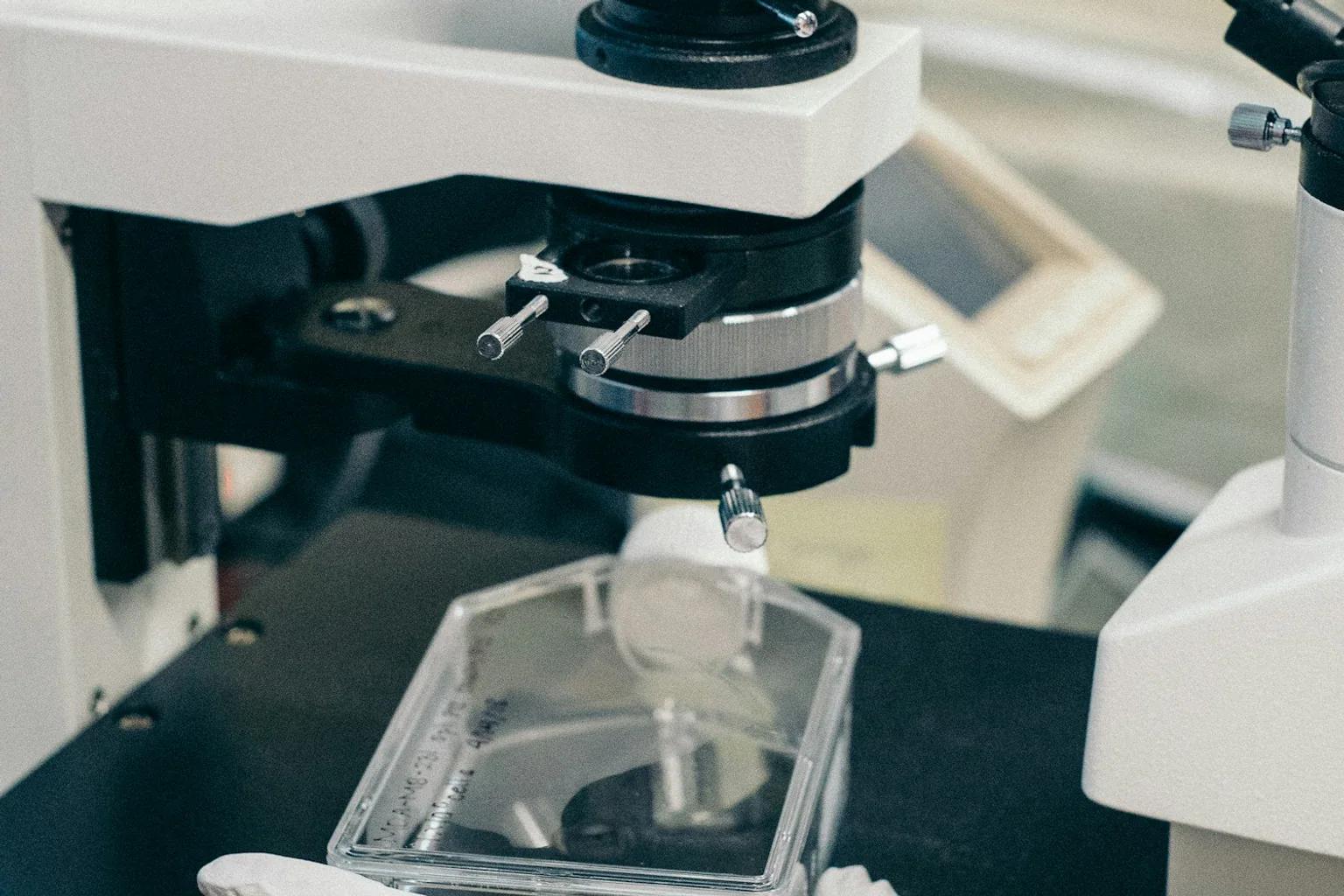 Technician inspecting a component through a laboratory microscope